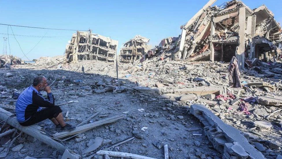 A Palestinian man sits among the the rubble after Israeli strikes on the towers of Al-Zahra city on 20 October 2023.