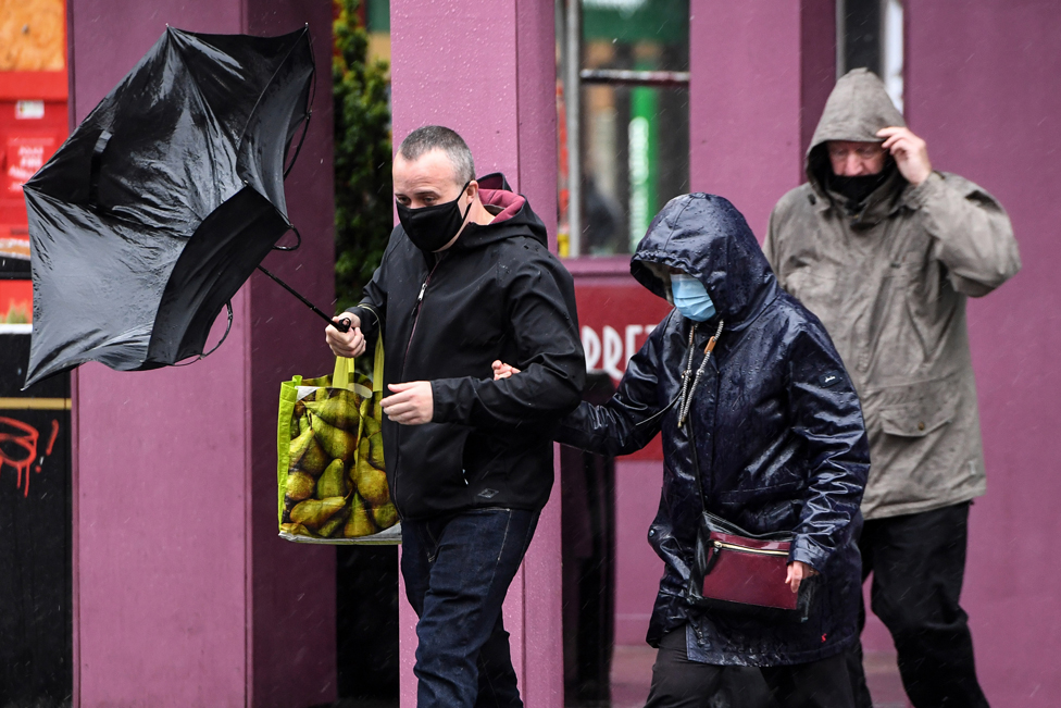 Pedestrians wearing protective face masks struggle against the wind in Glasgow city centre on August 25, 2020, as Storm Francis brings rain and high winds to the UK.