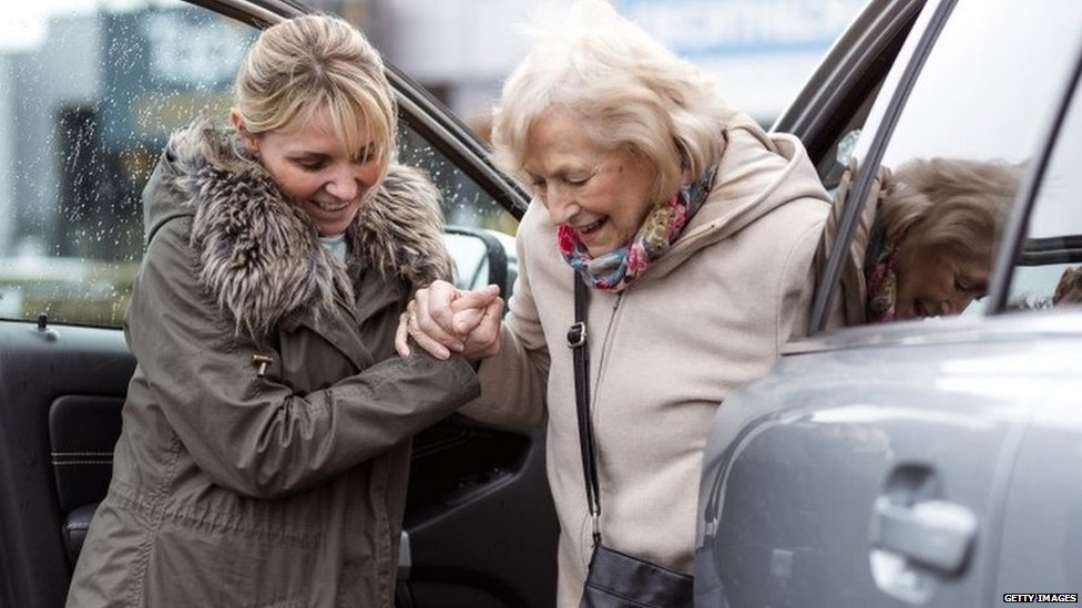 Девушка помогает пожилой женщине выйти из машины