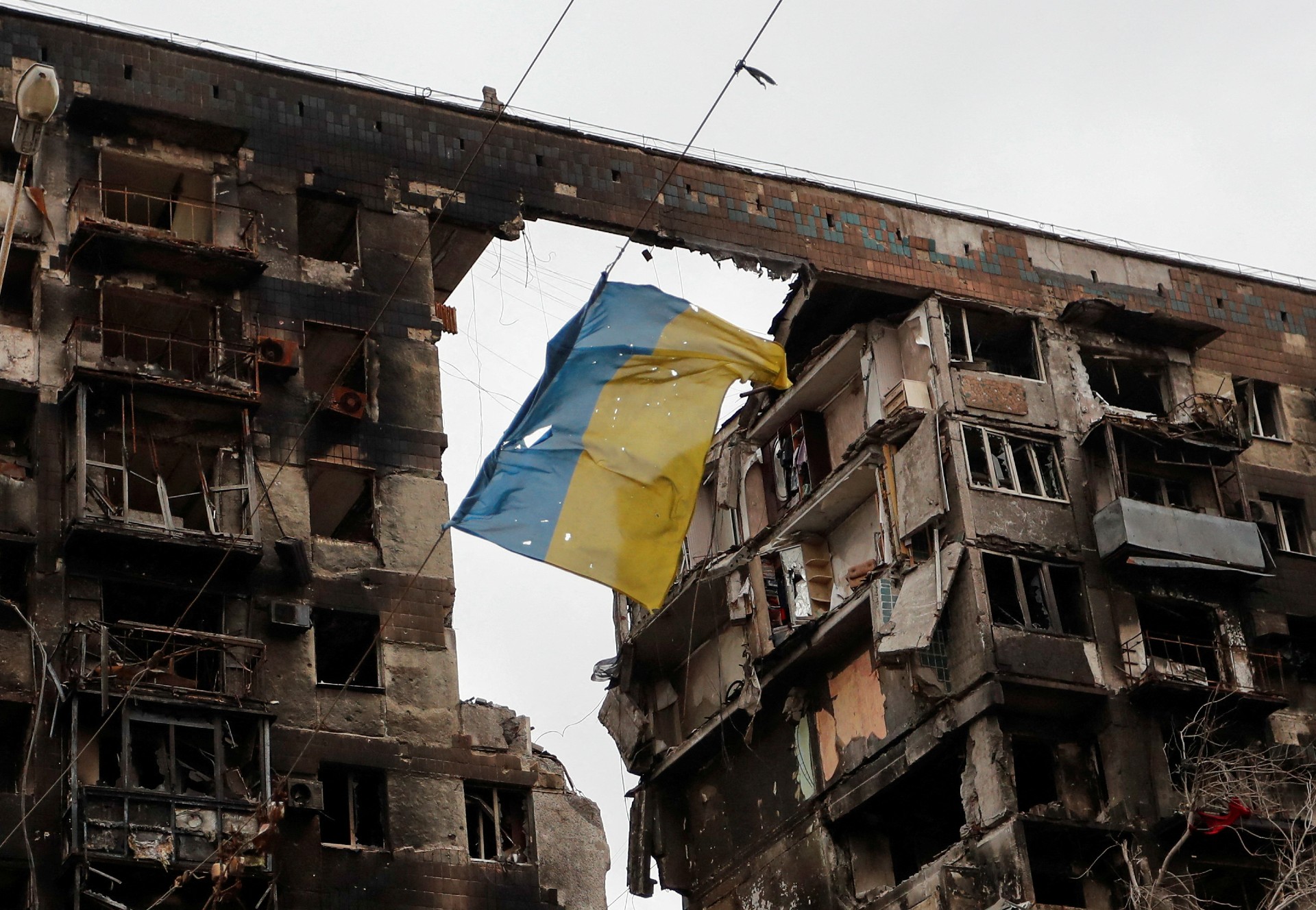 A Ukrainian flag flying from a badly damaged block of flats in Mariupol