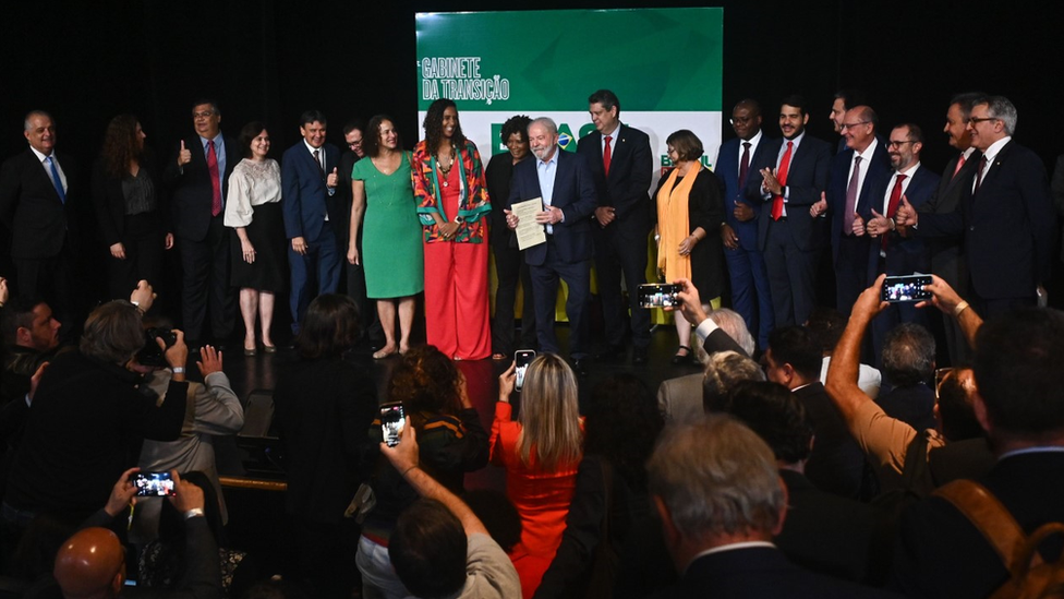 Lula e ministros anunciados no palco; a maioria aparece sorrindo