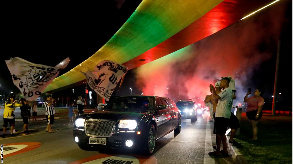 The hearse carrying Pele's coffin arrives to Santos as a firework goes off in the early morning