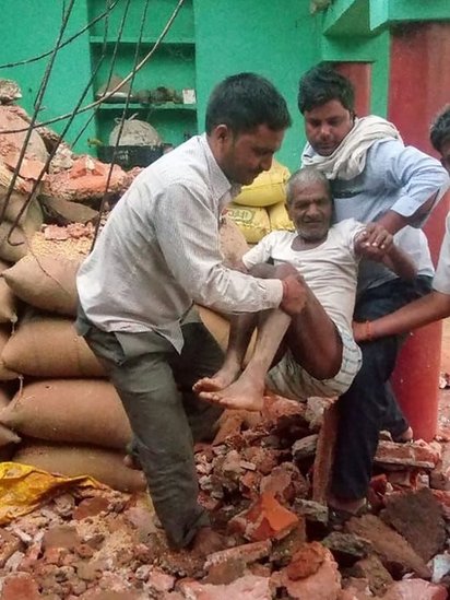 Spasioci iznose starca iz ruševina njegove kuće uništene u oluji u Indiji. 3. maj 2018