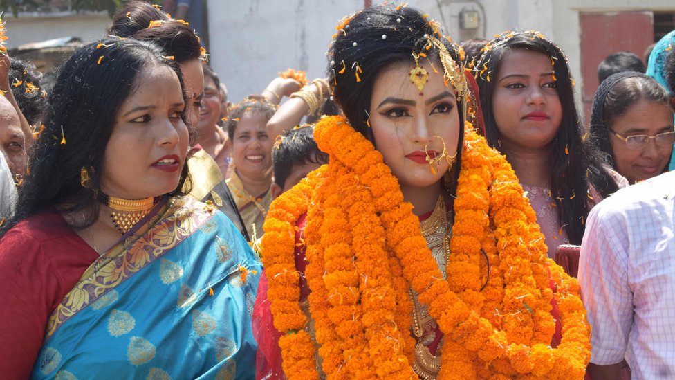 родственники жениха Тарикул Ислам приветствуют невесту Хадизу Актер Хуши (C) с цветочным венком, когда она прибывает в дом жениха во время их свадьбы в Мехерпуре
