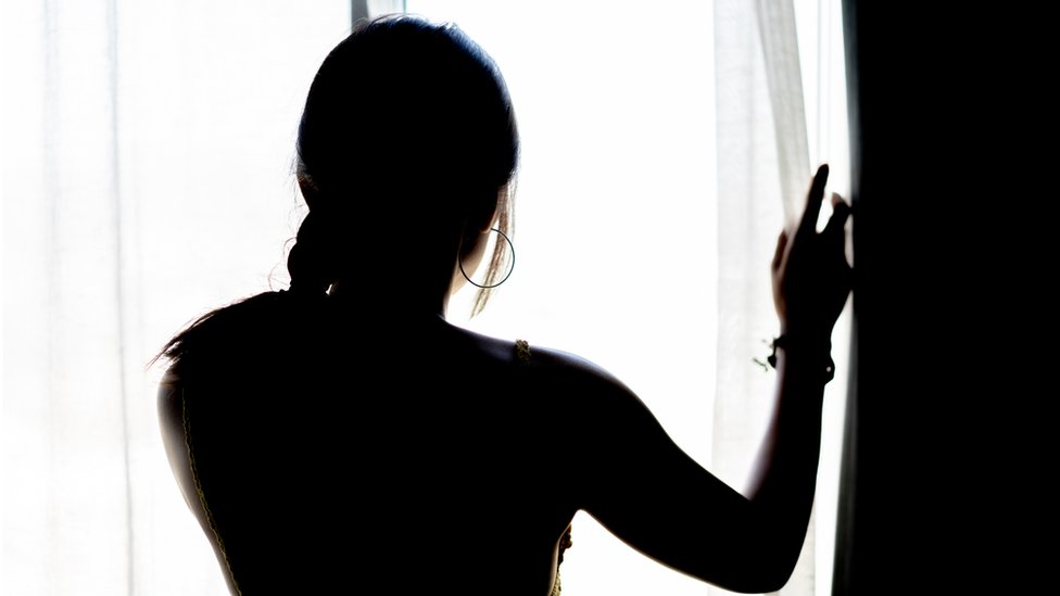 Женщина смотрит в окно, стоковое изображение