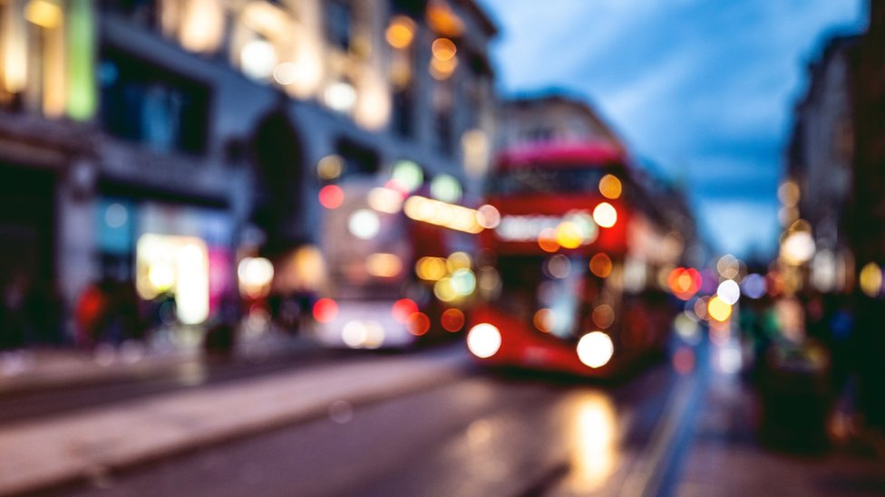 Автобус приближается к остановке на лондонской улице ночью