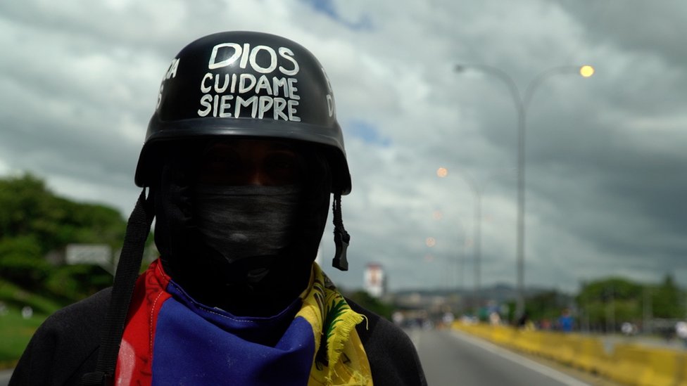 Протестующий в каске читает «Боже, защити меня всегда» в Каракасе