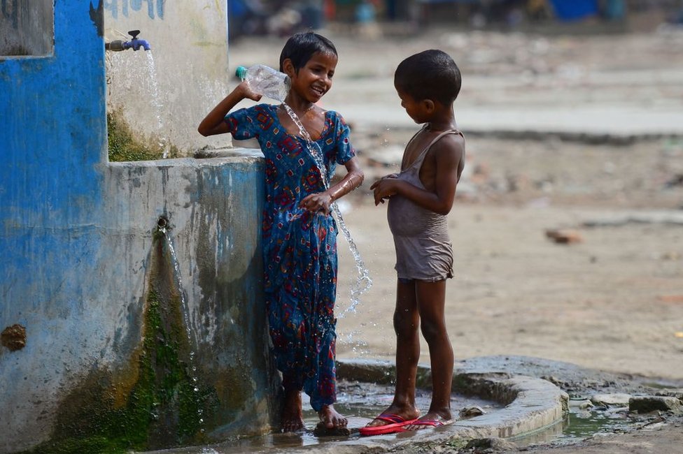 Индийские дети принимают ванну из крана у дороги жарким летним днем ??в Аллахабаде 2 июня 2019 г.