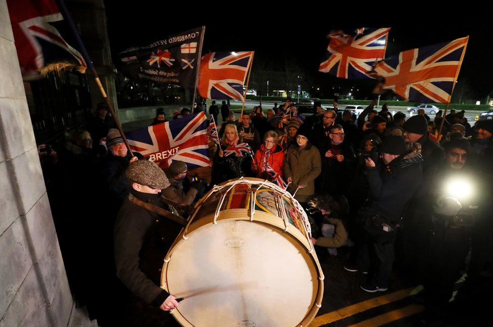 Люди собрались возле поместья Стормонт в Белфасте, размахивая флагами профсоюзов, чтобы отметить момент Брексита