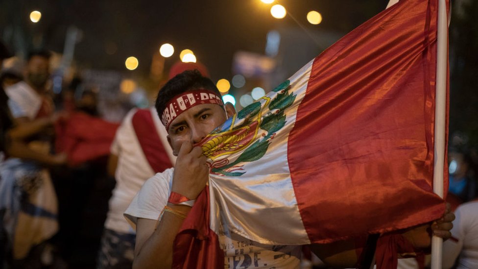 joven en la protesta con una bandera de Perú