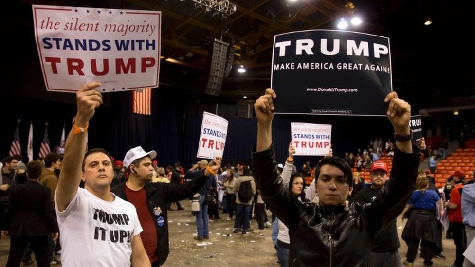 Сторонники Трампа держат плакаты во время митинга Трампа в павильоне МСЖД в Чикаго