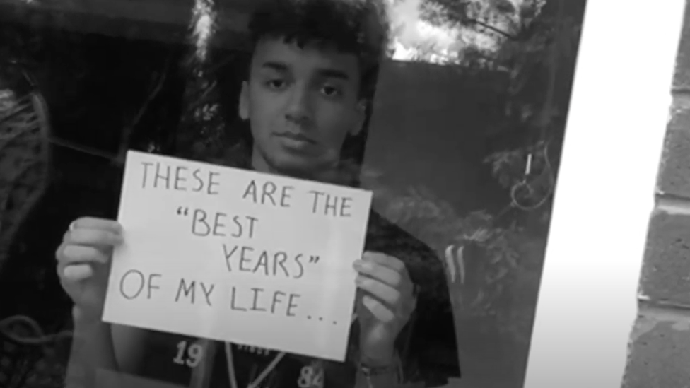Молодой человек держит табличку с надписью «Это лучшие годы моей жизни»