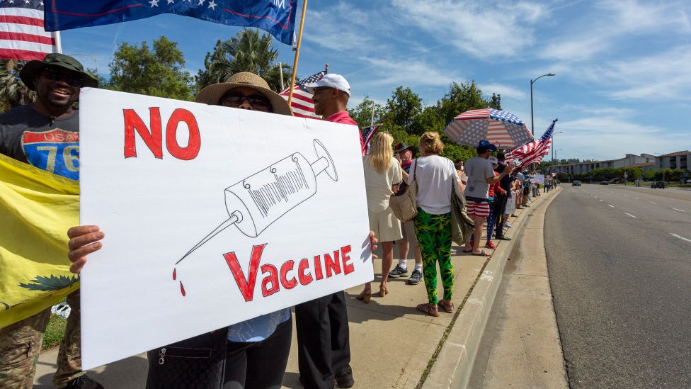 Persona sostiene una cartel donde se lee "No vaccine" (No a la vacuna) durante una protesta en Estados Unidos.