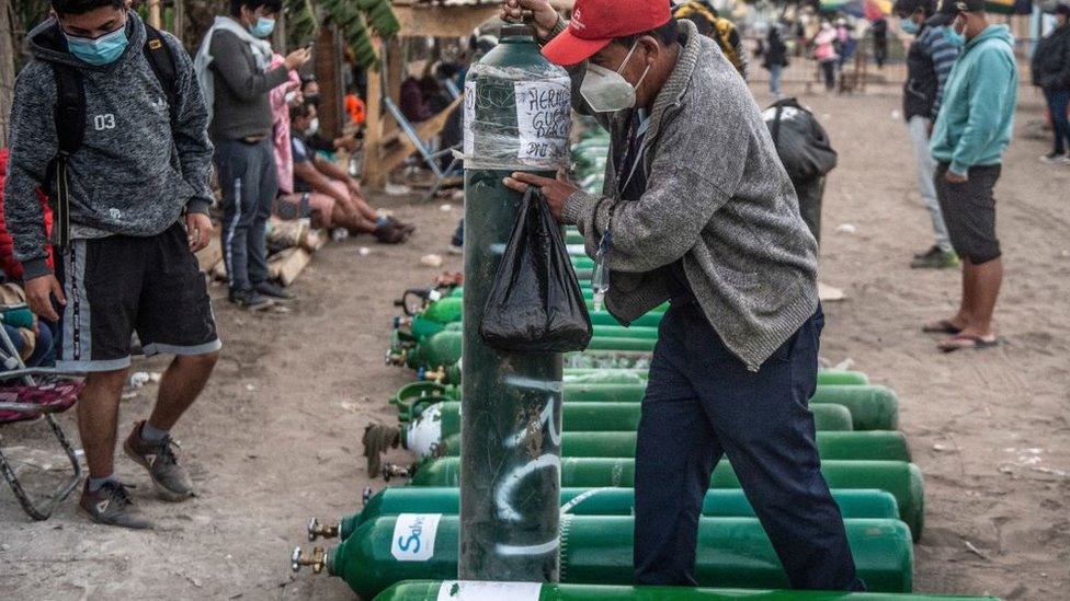 Homem levantando cilindro de oxigênio em Lima, em abril de 2021