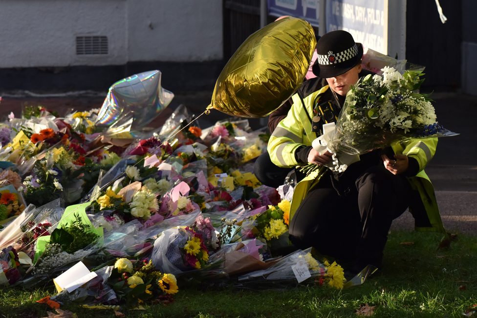 شرطية تنقل أزهارا لتأبين إيميس من أمام كنيسة