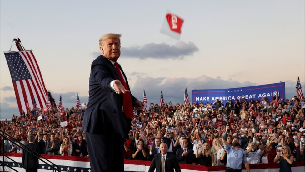 President Donald Trump throws a facemask into the crowd at a rally in Sanford, FL 12 October 2020