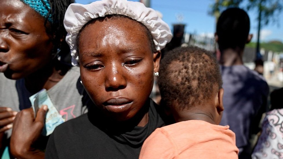 Una mujer haitiana llorando con su niño en brazos.