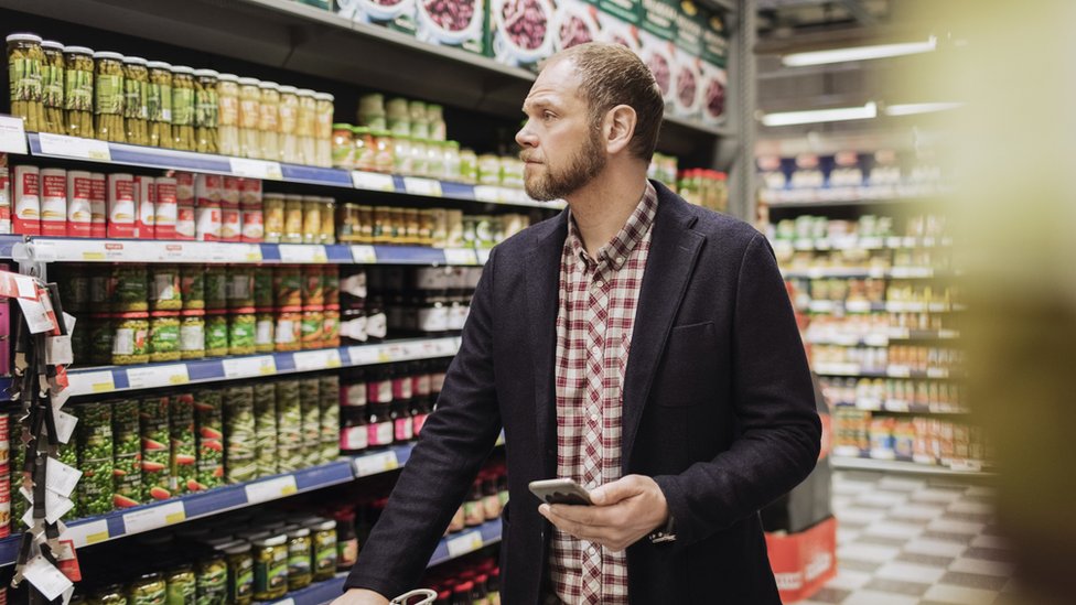 Hombre en el supermercado con una lista en el celular