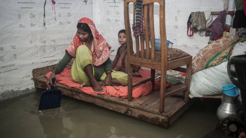 Mulher e menina em cômodo inundado em Chittagong