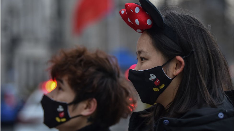Two customers wearing facemasks with Mickey Mouse at a Disney park