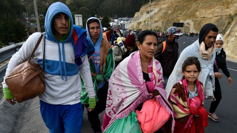 Migrantes venezuelanos caminhando em estrada