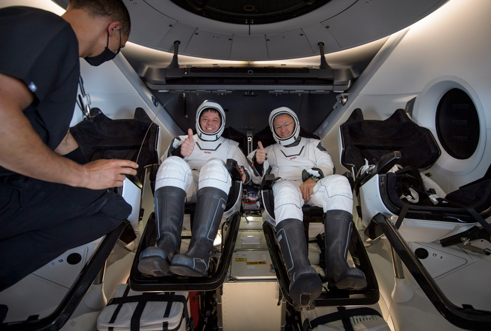 Astronauts Robert Behnken and Douglas Hurley give a thumbs up as they sit inside the SpaceX Crew Dragon Endeavour spacecraft