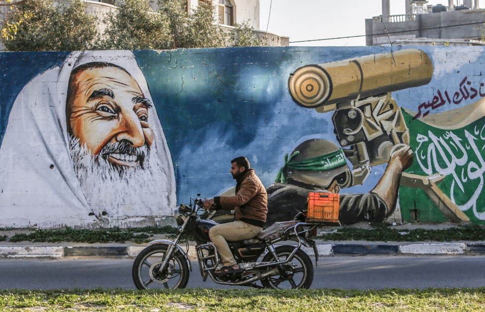 A Palestinian man drives a motorcycle past a mural depicting late Hamas spiritual leader Sheikh Ahmed Yassin