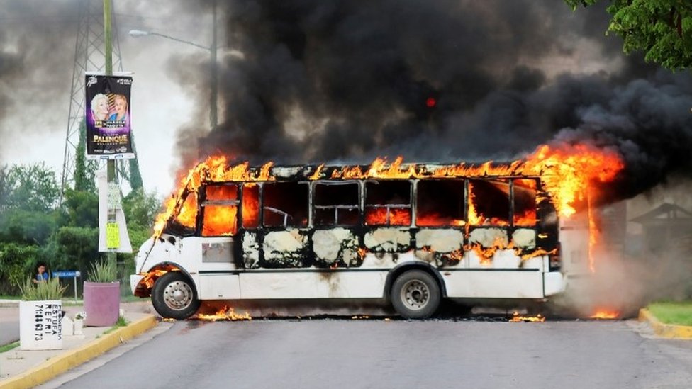 Горящий автобус, подожженный боевиками картеля, чтобы перекрыть дорогу, изображен во время столкновений в Кулиакане