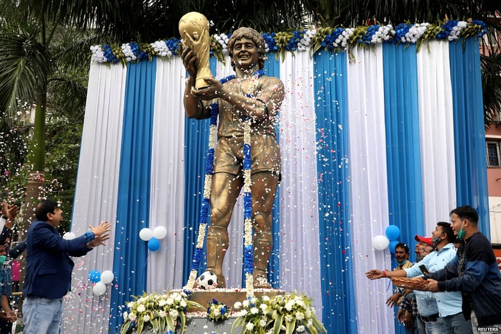 Люди осыпают лепестками статую великого аргентинского футболиста Диего Марадоны во время молитвенного собрания, посвященного его памяти, в Калькутте, Индия, 26 ноября 2020 года