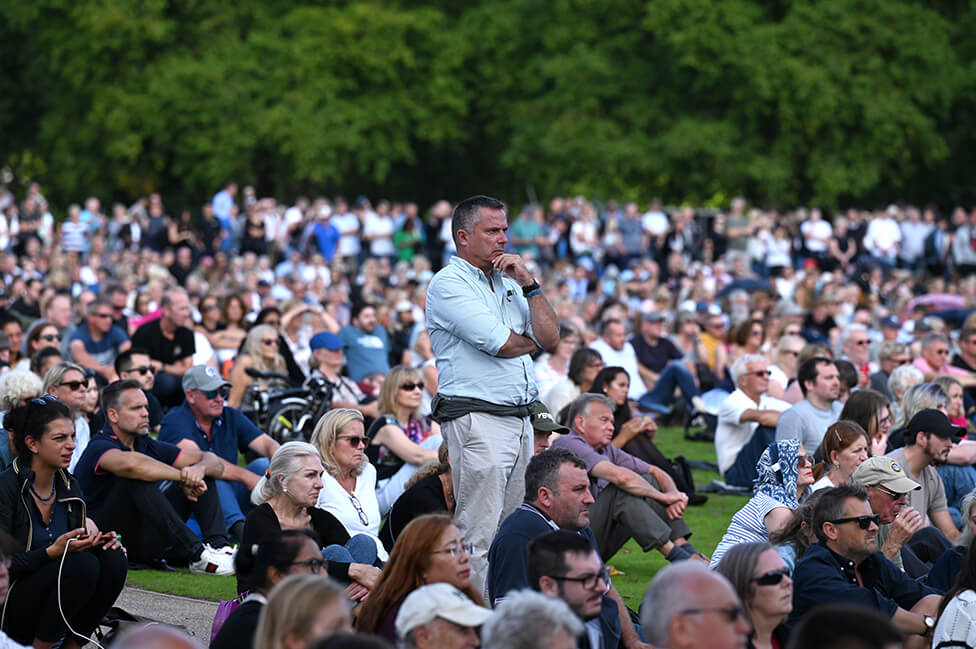 A crowd of people watch the procession on a large screen in Hyde Park