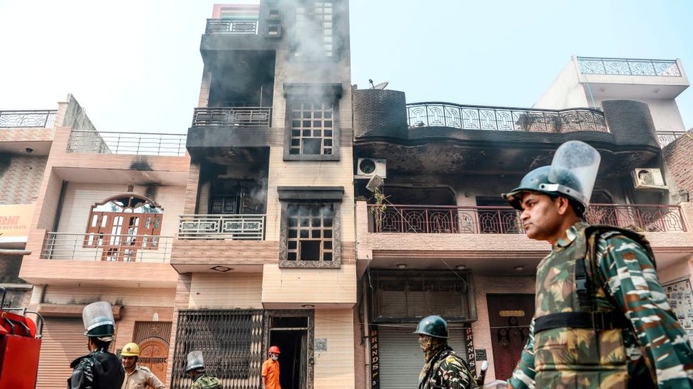 دورية أمنية تمرّ من أمام منازل محترقة ومتهدمة بعد مصادمات بين متظاهرين مؤيدين وآخرين معارضين لقانون المواطَنة الجديد في الهند، في نيودلهي في 26 فبراير/شباط 2020