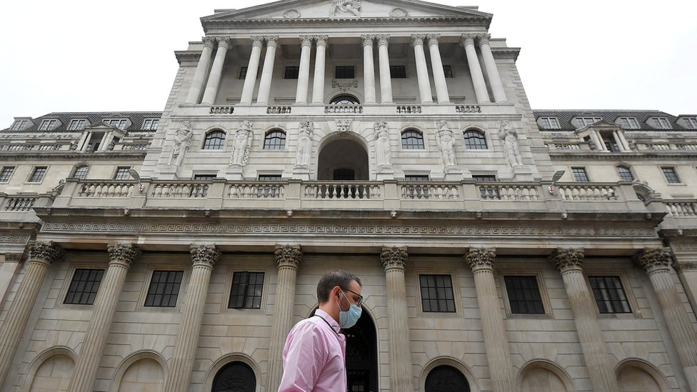Мужчина в маске проходит мимо Банка Англии в лондонском Сити