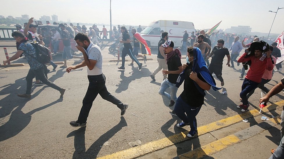 Иракские протестующие бегут в поисках прикрытия, поскольку силы безопасности используют слезоточивый газ для разгона толпы в центре Багдада во время антиправительственных демонстраций в иракской столице 25 октября 2019 г.