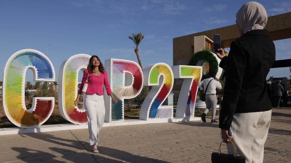 People taking photos by a giant COP27 logo at Sharm El-Sheikh