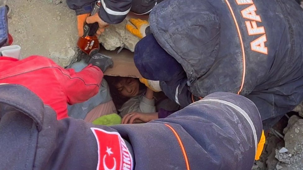 A girl is rescued from under a collapsed building.