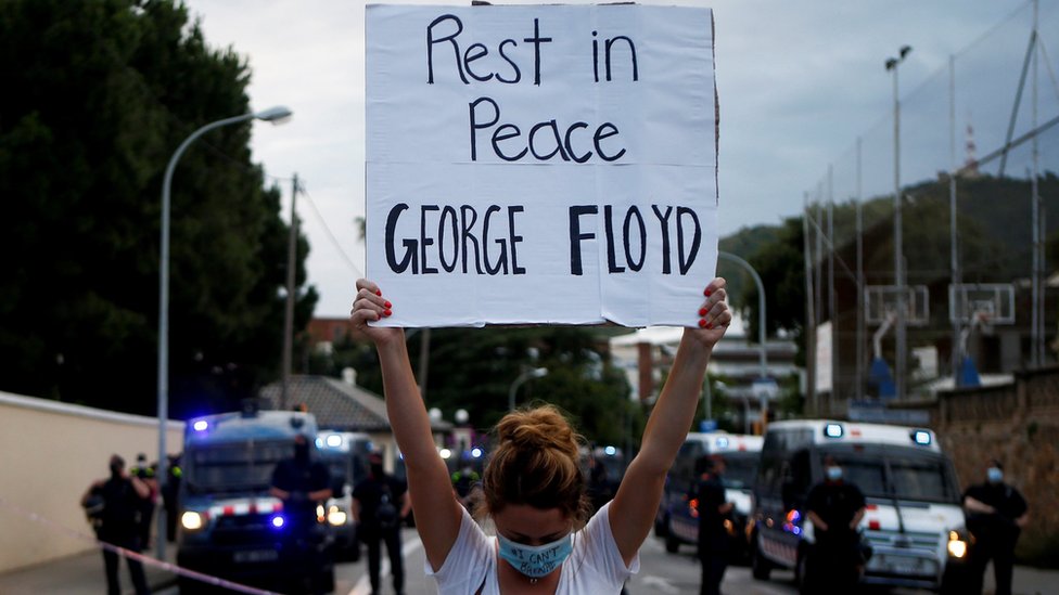 Женщина держит табличку с надписью «Покойся с миром, Джордж Флойд» возле консульства США в Барселоне