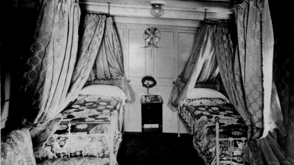 Foto em preto e branco de uma cabine com duas camas de luxo