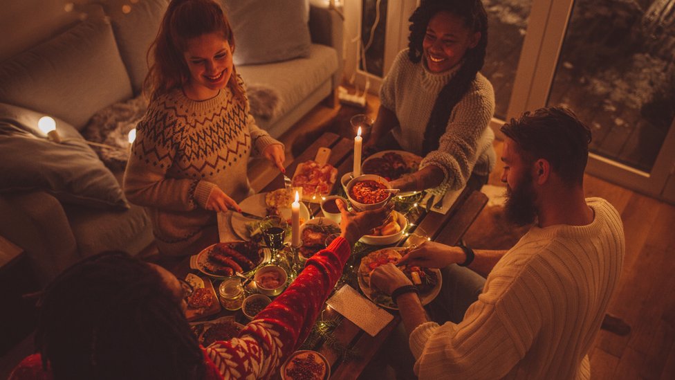Друзья устраивают рождественский ужин дома (общее изображение)