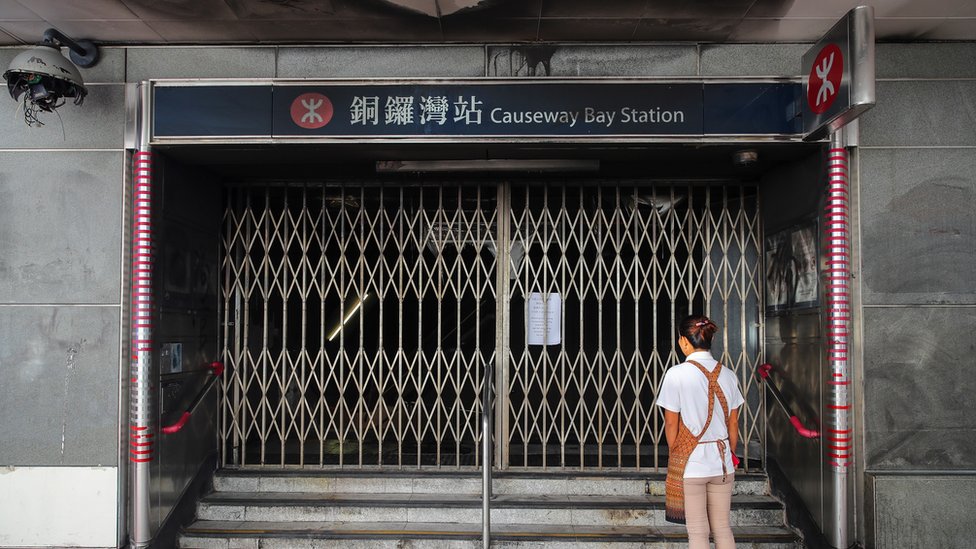 Женщина стоит у закрытых ворот станции метро Causeway Bay в Гонконге, Китай, 5 октября 2019 г.
