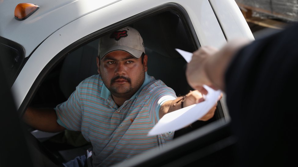Мексиканский дальнобойщик передает документы манифеста сотруднику таможни и пограничной службы США в Ларедо, штат Техас (17 октября 2016 г.)