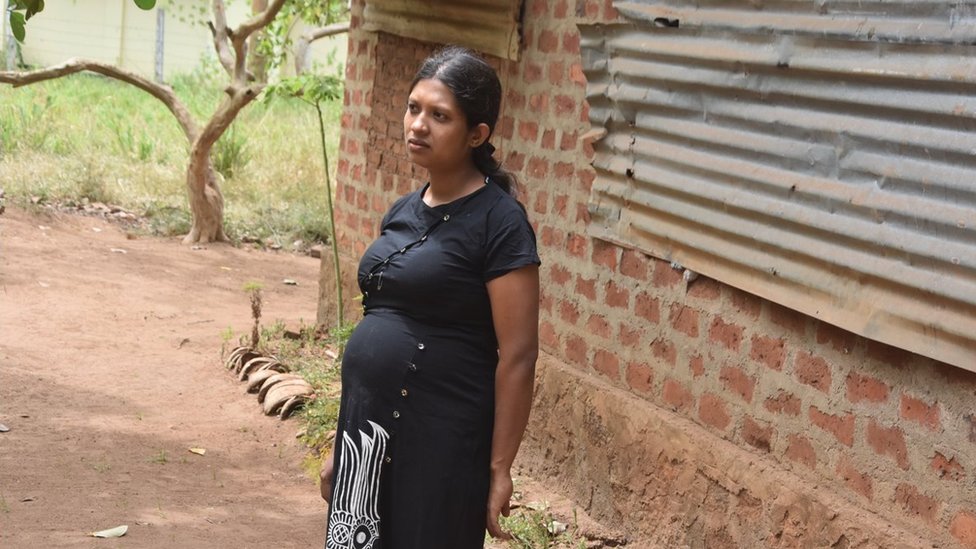 Thakshila Niroshini, a 27-year-old pregnant mother from Vavuniya in northern Sri Lanka stands outside a building