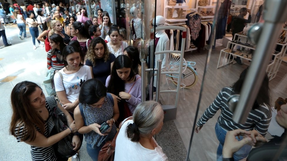 Grupo de personas haciendo fila delante de un comercio en Venezuela