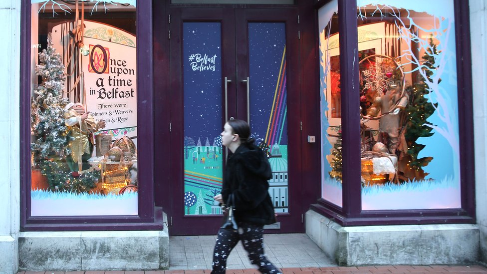 Женщина проходит мимо закрытого магазина в Белфасте