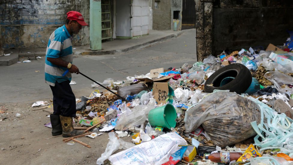 Un hombre revisa la basura en Venezuela.