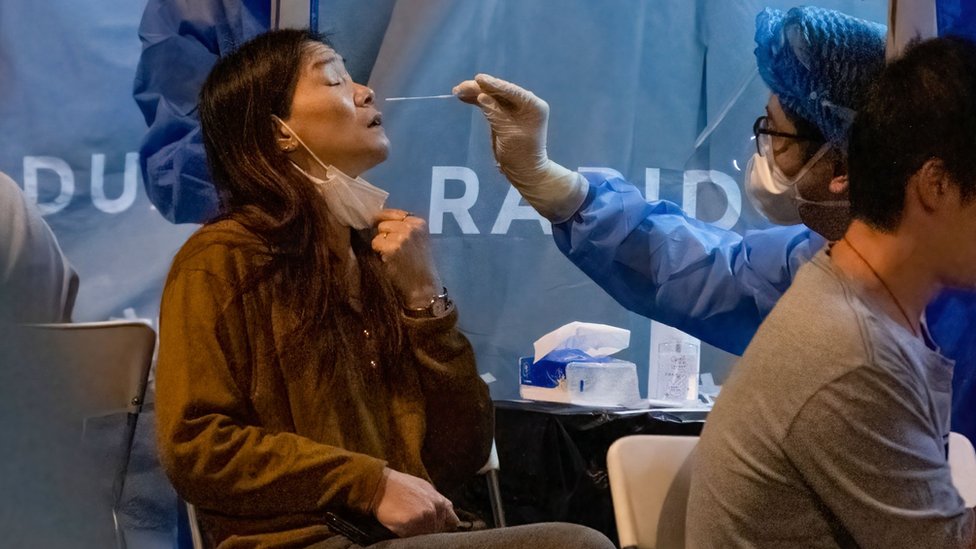 醫護人員在香港九龍油麻地一處臨時封鎖區內給一位居民採樣檢測新冠病毒（4/2/2021）