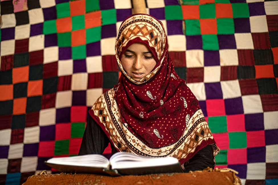 امرأة تقرأ القرآن في مخيم الكبش للنازحين في الريف بالقرب من مدينة الرقة شمال سوريا في 7 أبريل/نيسان 2022