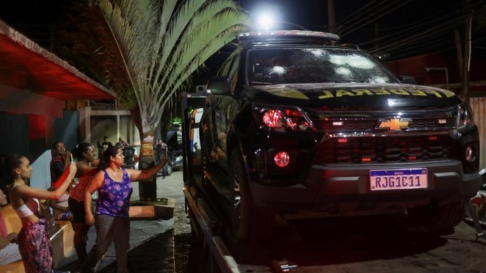 Local residents take pictures of a damaged police car in Levy Gasparian, Rio de Janeiro state, Brazil. Photo: 23 October 2022