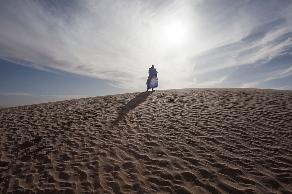 Un hombre camina sobre la arena del desierto a las afueras de Tombuctú el 19 de enero de 2010 en Tombuctú, Malí.