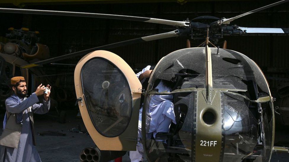 مقاتل من طالبان يلتقط صورة لزميله داخل طائرة مروحية من طراز إم دي-530