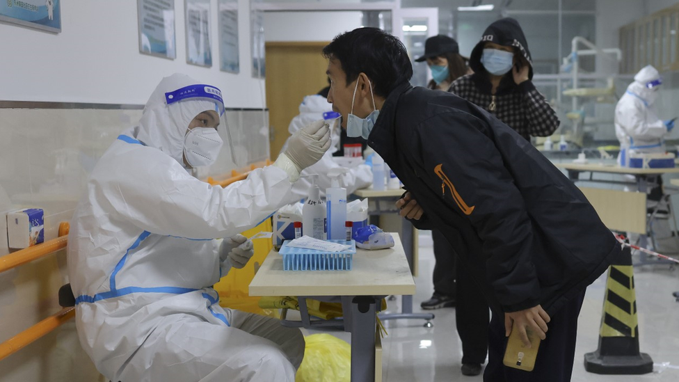 عامل صحي يأخذ عينات مسحة من رجل كجزء في برنامج الصين للاختبار الجماعي لفيروس كورونا